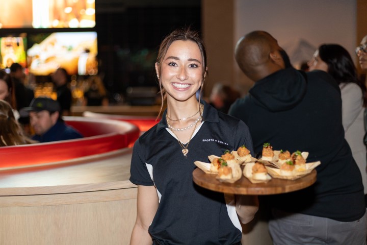 Sports & Social waitress holding tray of food.