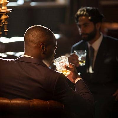 Two men in suites drinking cocktails in an upscale bar lounge.