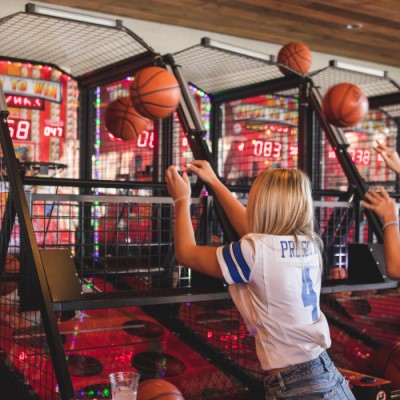 Woman playing arcade basketball game at Sports & Social.