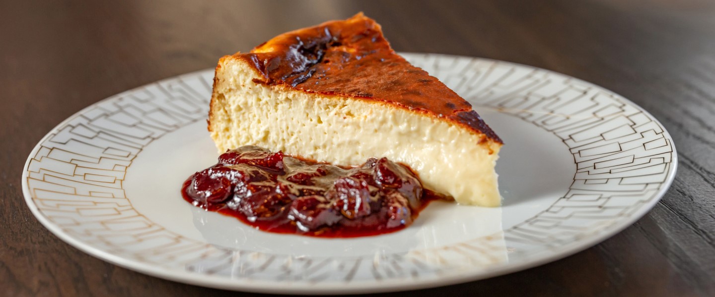 Basque cheesecake with sour cherries on a white plate.